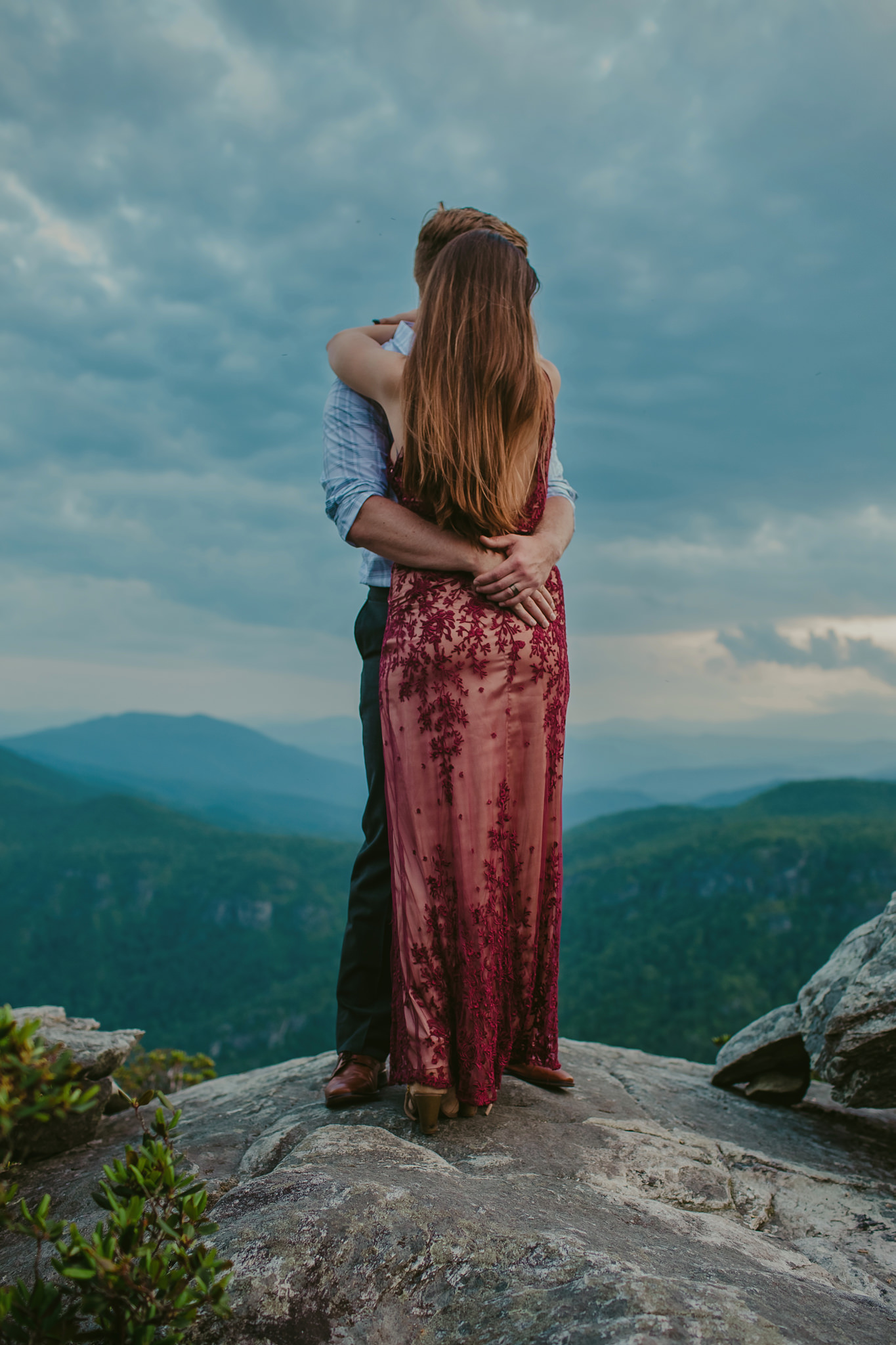 Woman in a red dress against the blue ridge mountains of North Carolina on top of Hawksbill