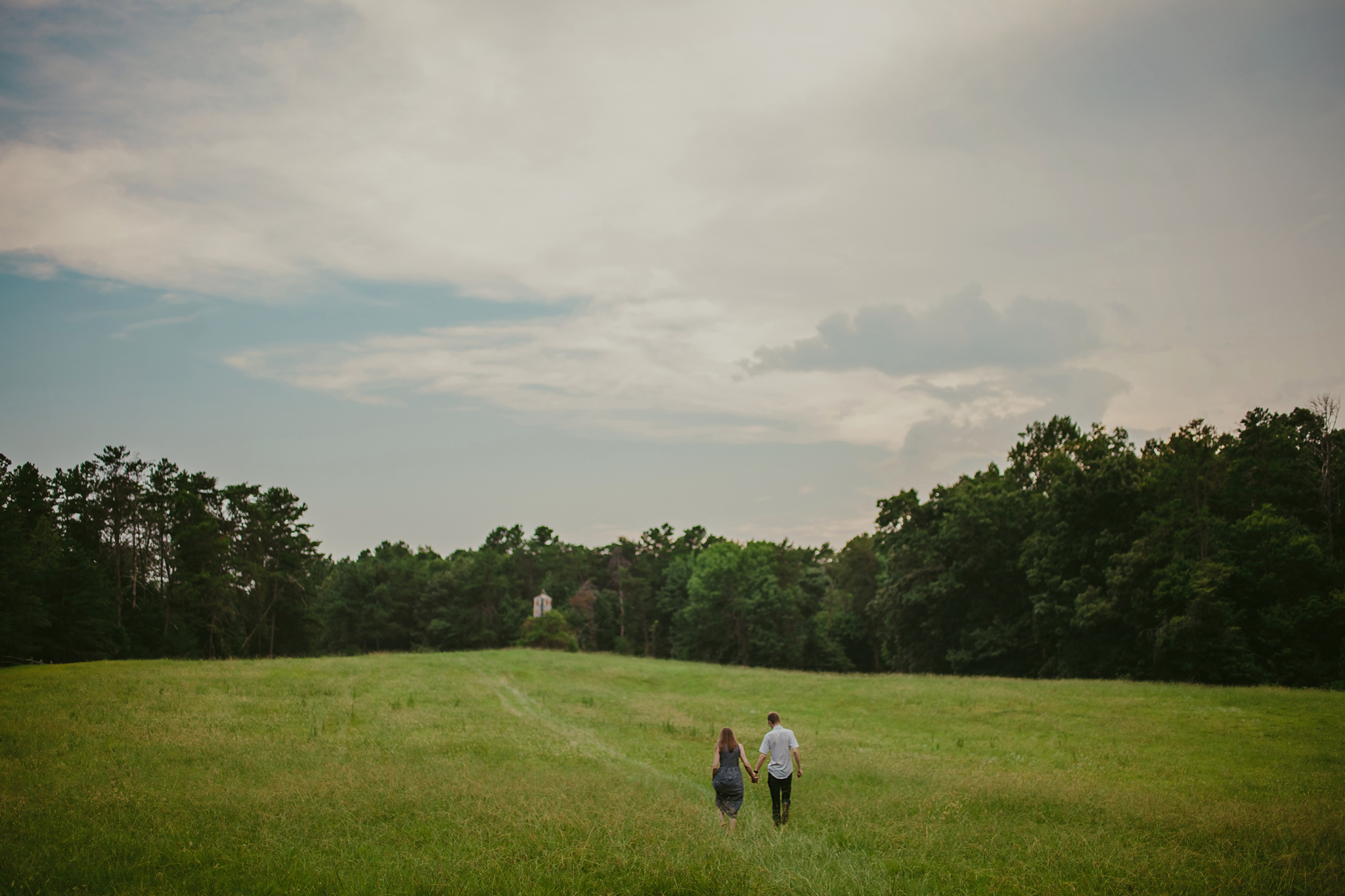 Couple wanders through a field in Greensboro, NC at the Timberlake Earth Sanctuary