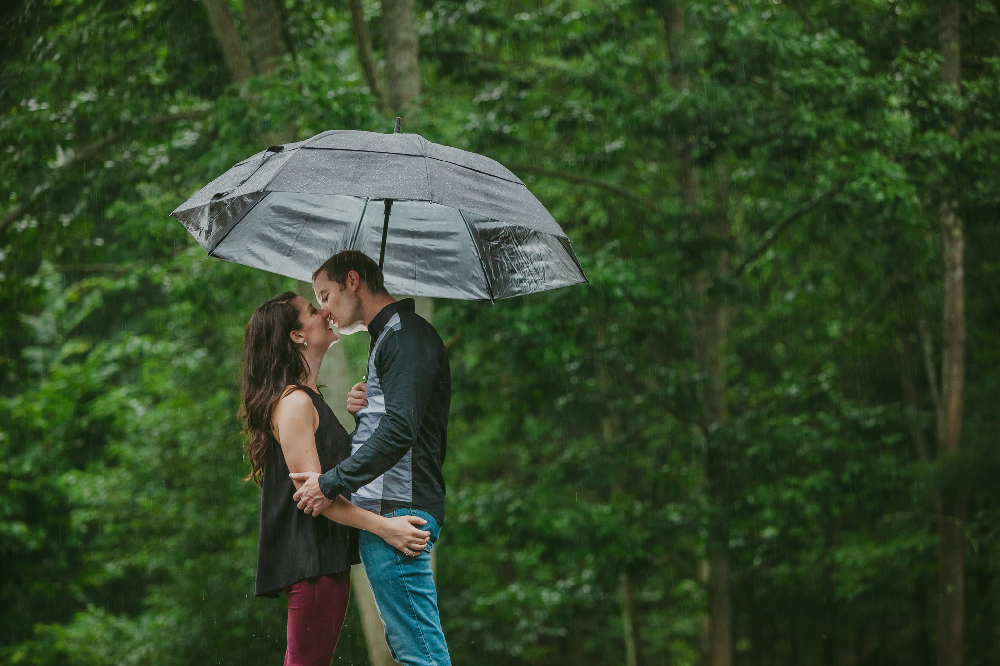 Couple kisses under an umbrella in the rain in Charlotte, NC