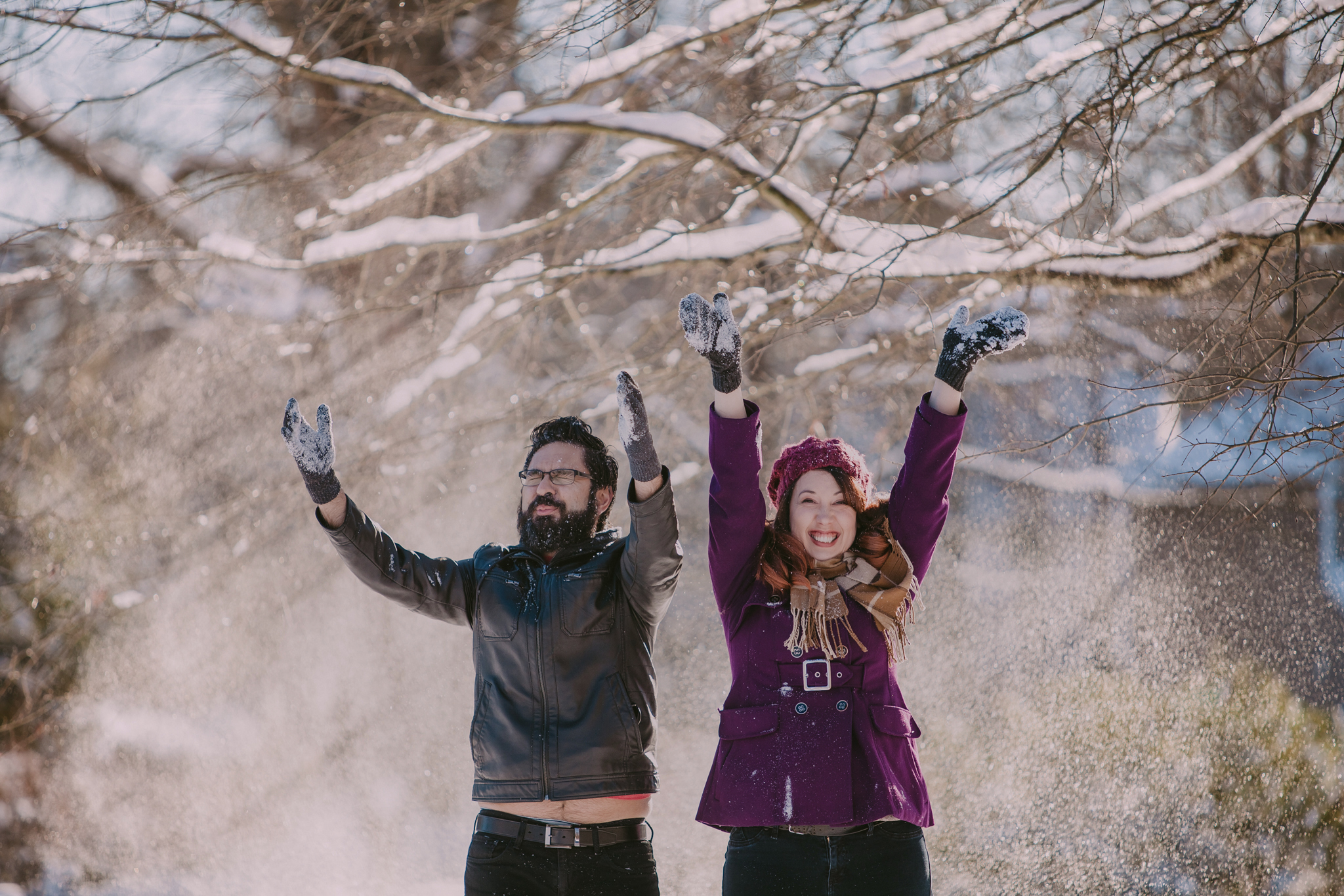 Couple throws snow into the air making silly faces in Charlotte, NC