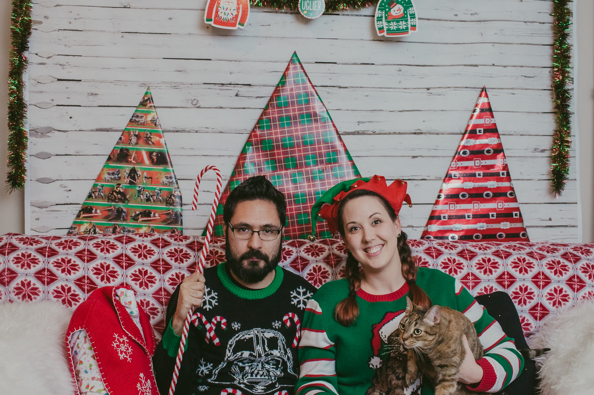 couple poses for a ugly sweater Christmas card with their cat in Charlotte, NC