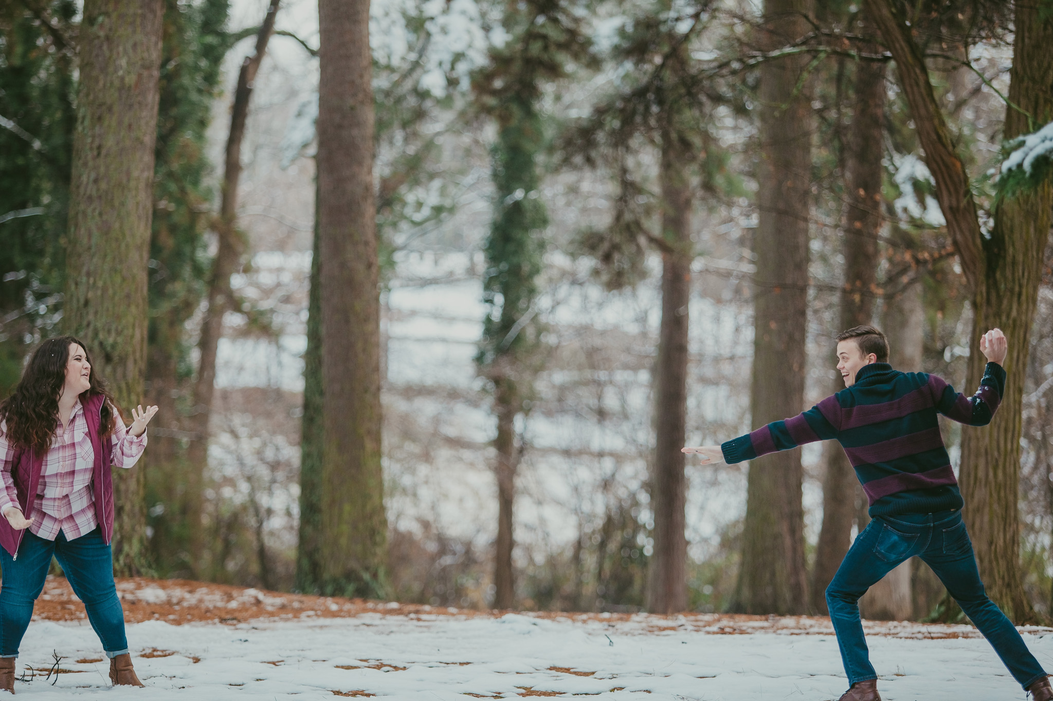 Couple plays in the snow at their engagement session at Mac Anderson Park