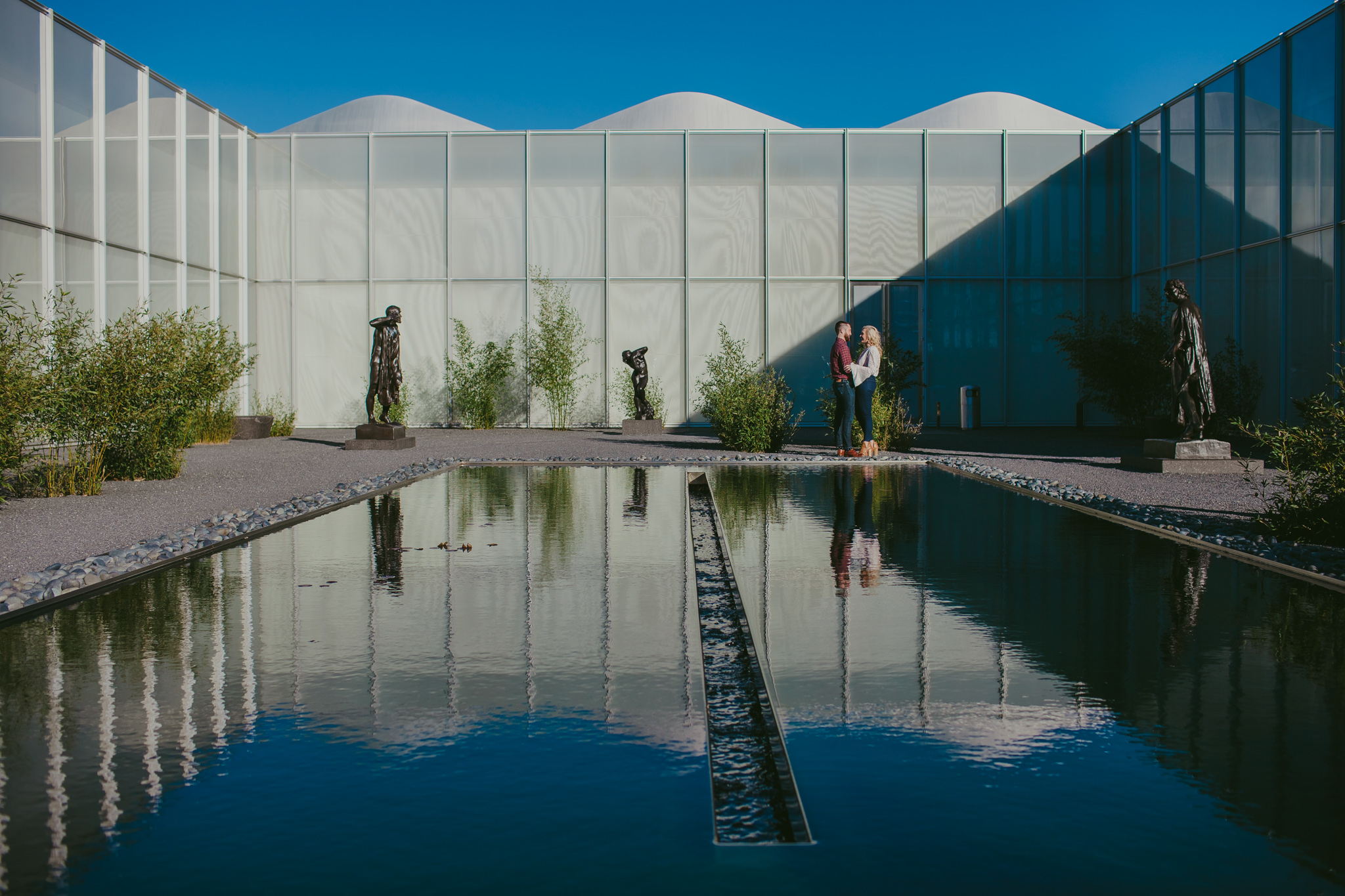 A pool of water reflects a sweet couple at the NC Museum of Art