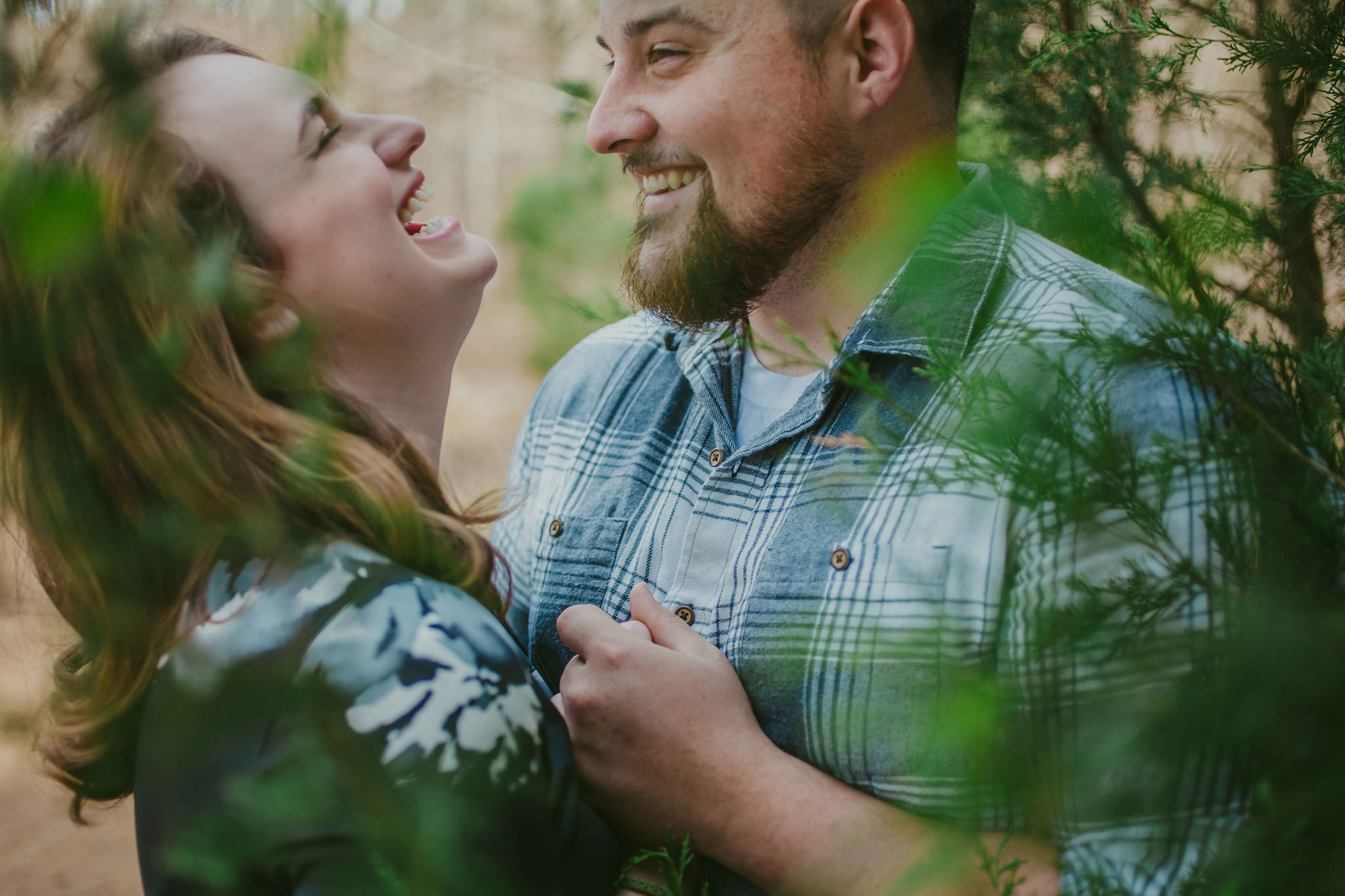 Couple laughs in Lake Norman State Park near Mooresville, NC for engagement photos