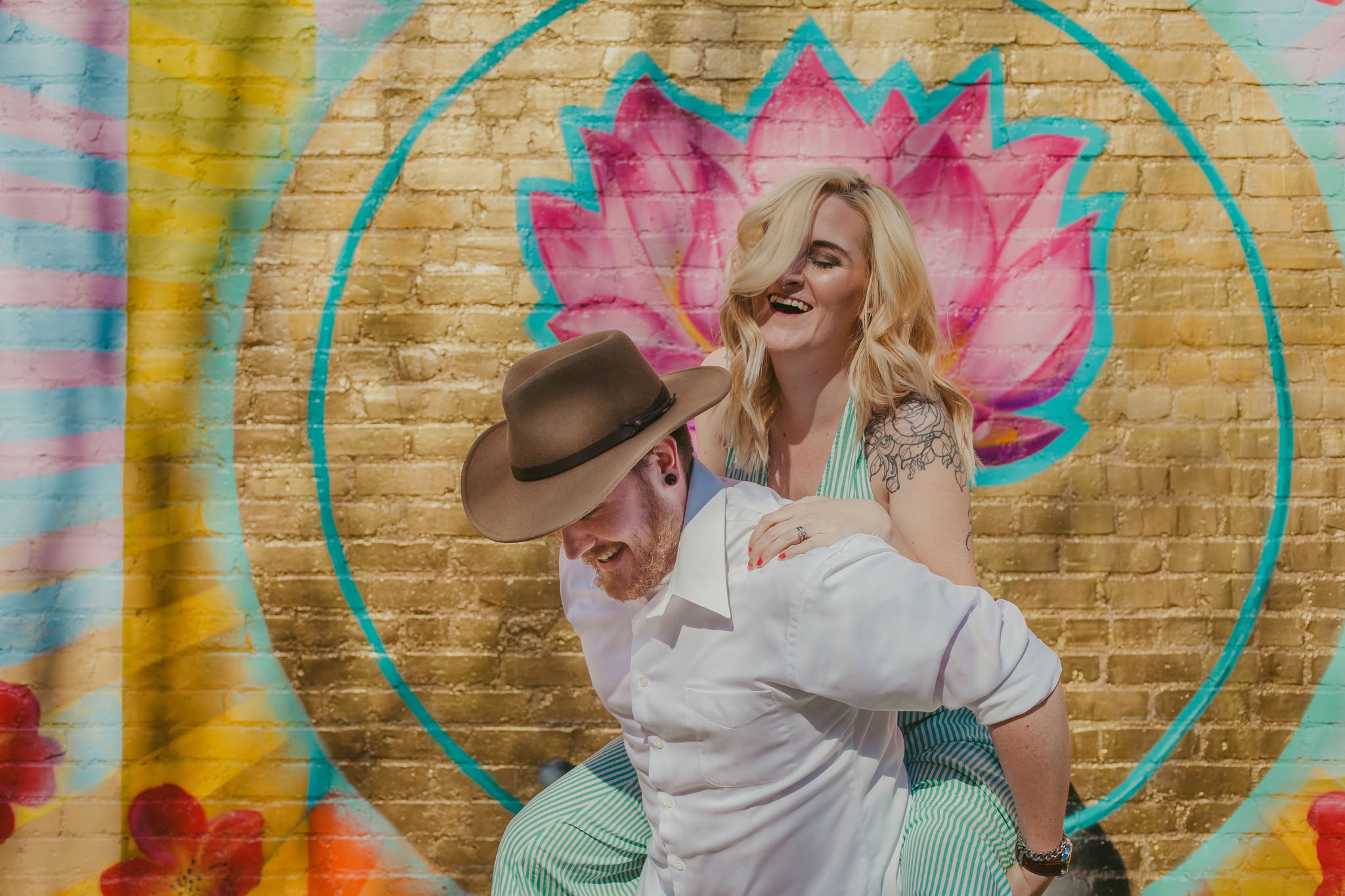 Husband gives his wife a piggy back ride for their colorful NoDa maternity session