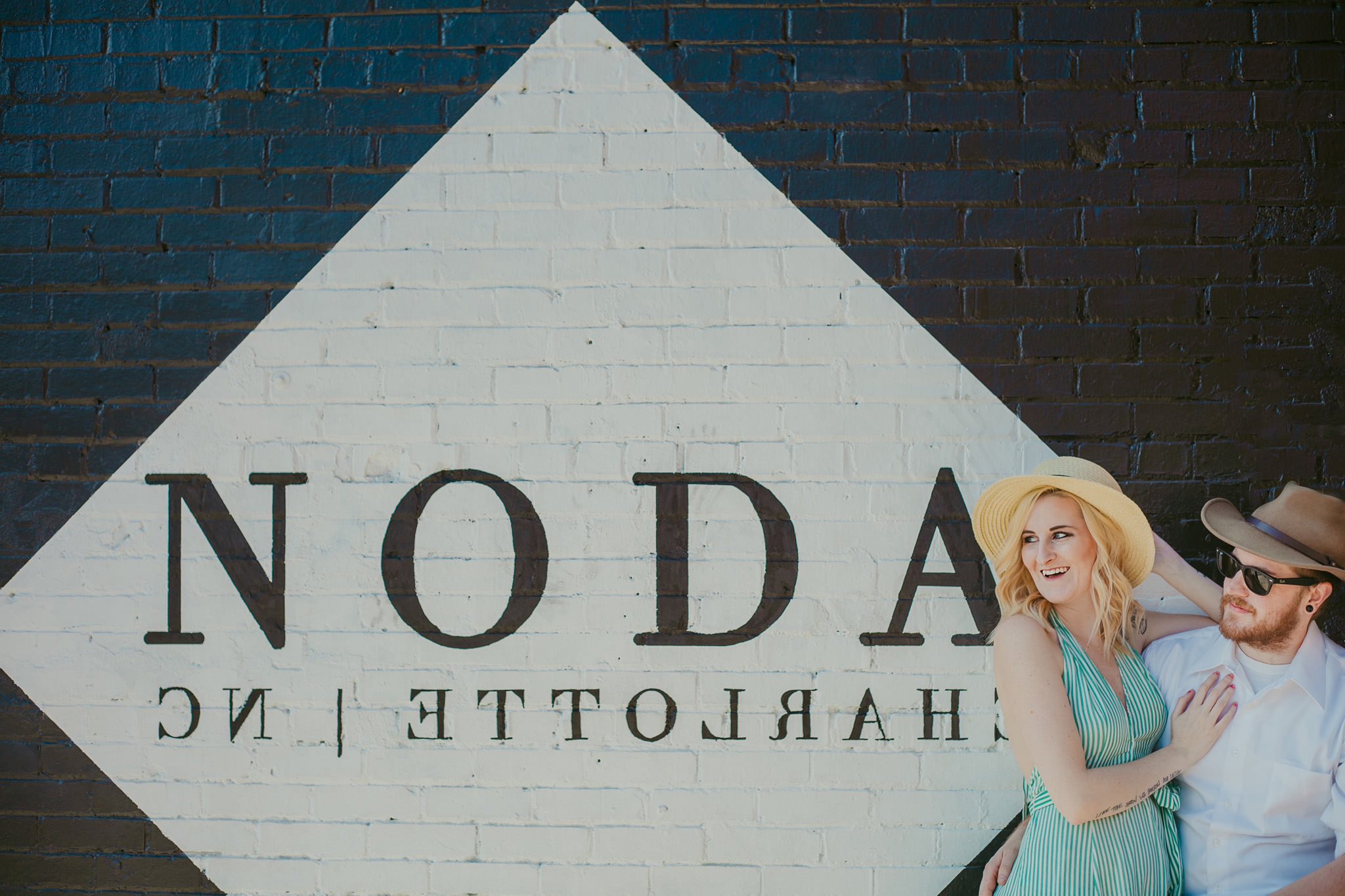 Couple poses at the NoDa sign in Charlotte NC for their maternity session