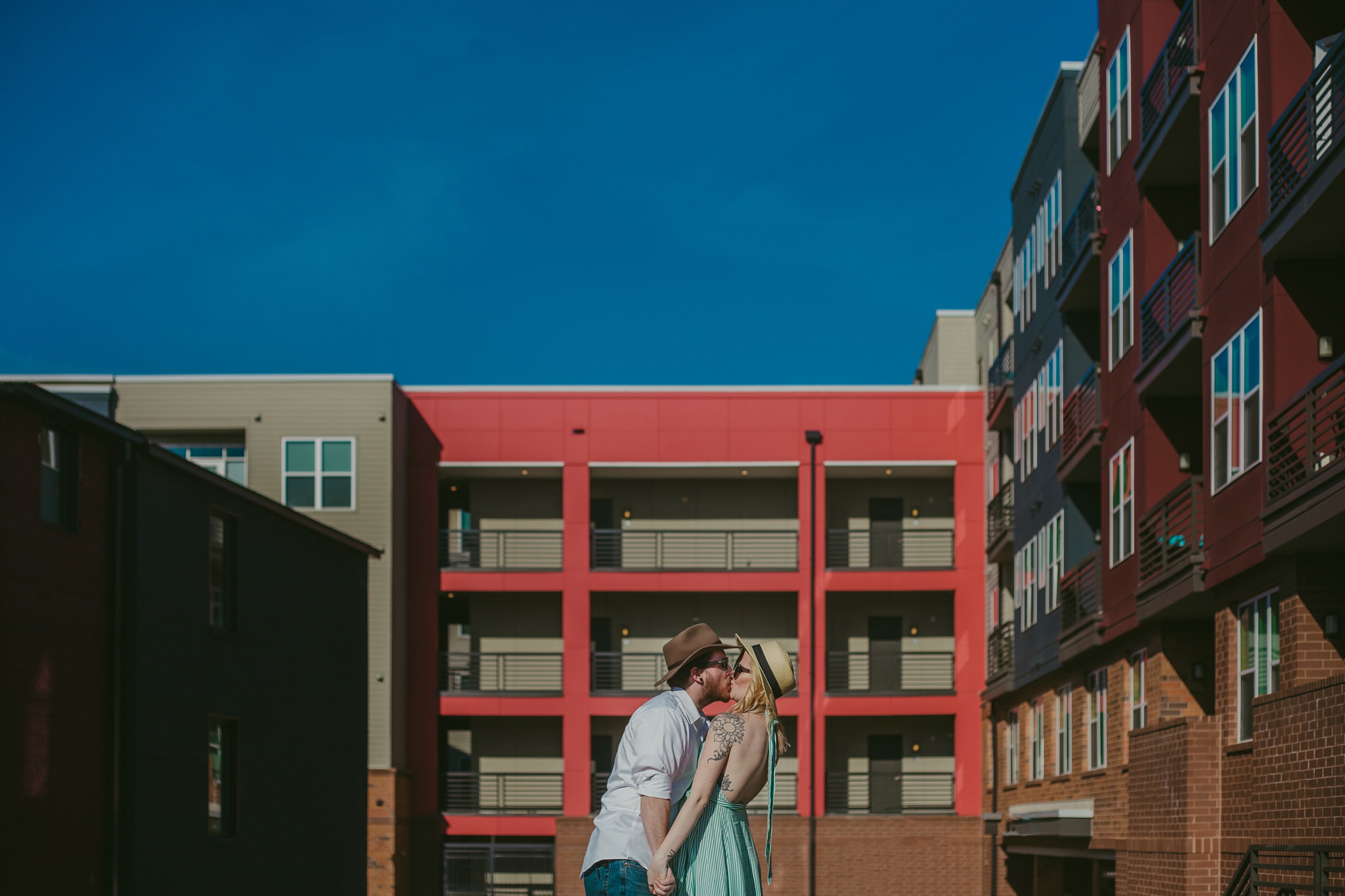 couple kisses on a street during their colorful NoDa maternity session