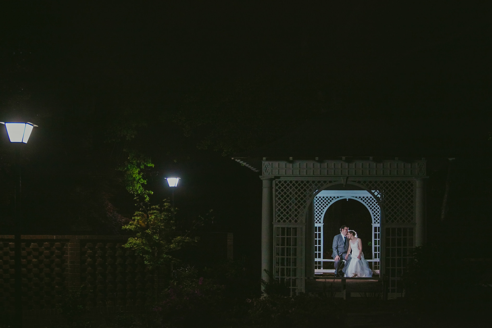 A bride a groom sneak a moment away from the party for a snuggle in the gazebo at the Shuford House in Hickory