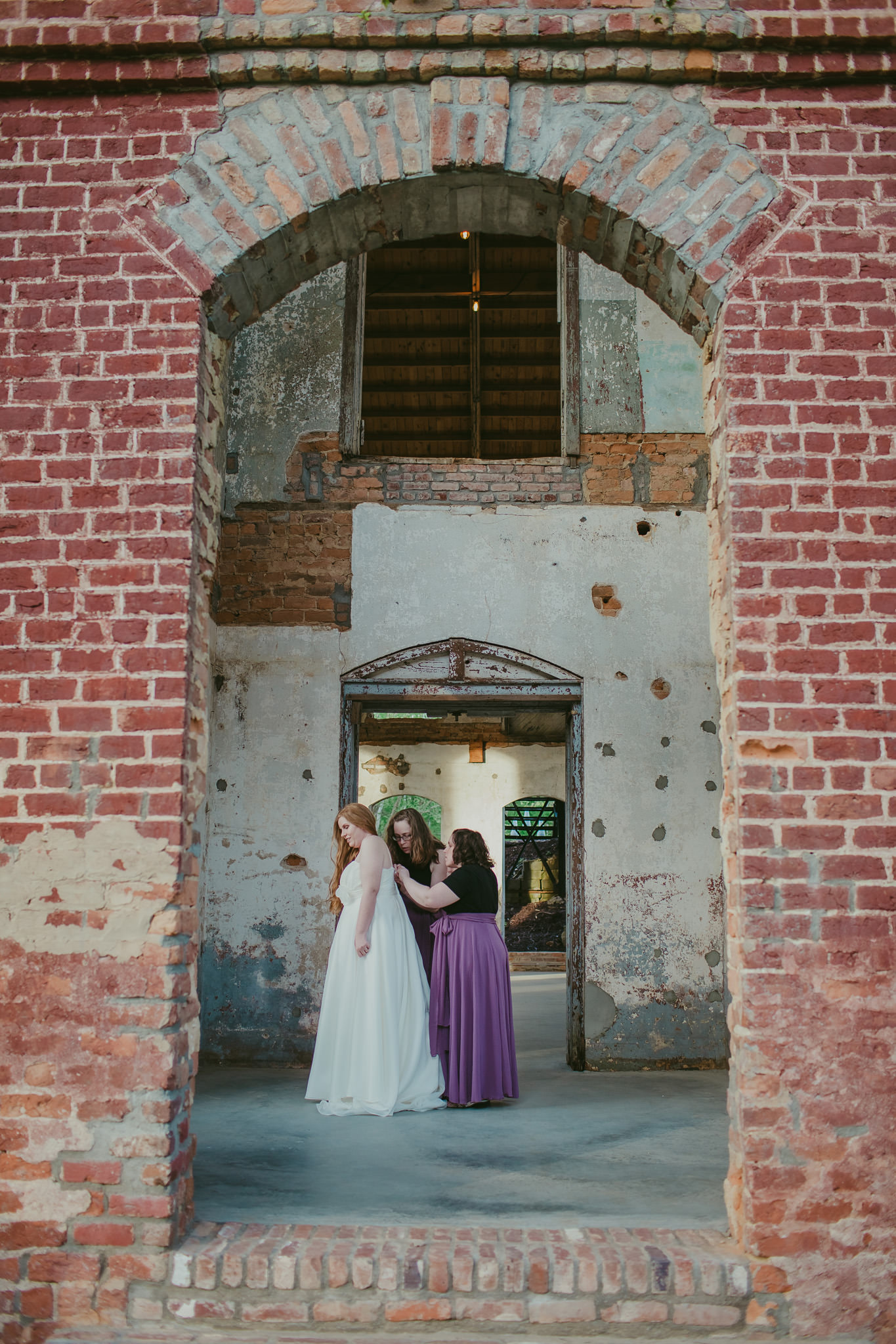 Bridesmaids help the bride into her wedding gown at the Providence Cotton Mill in Maiden, NC