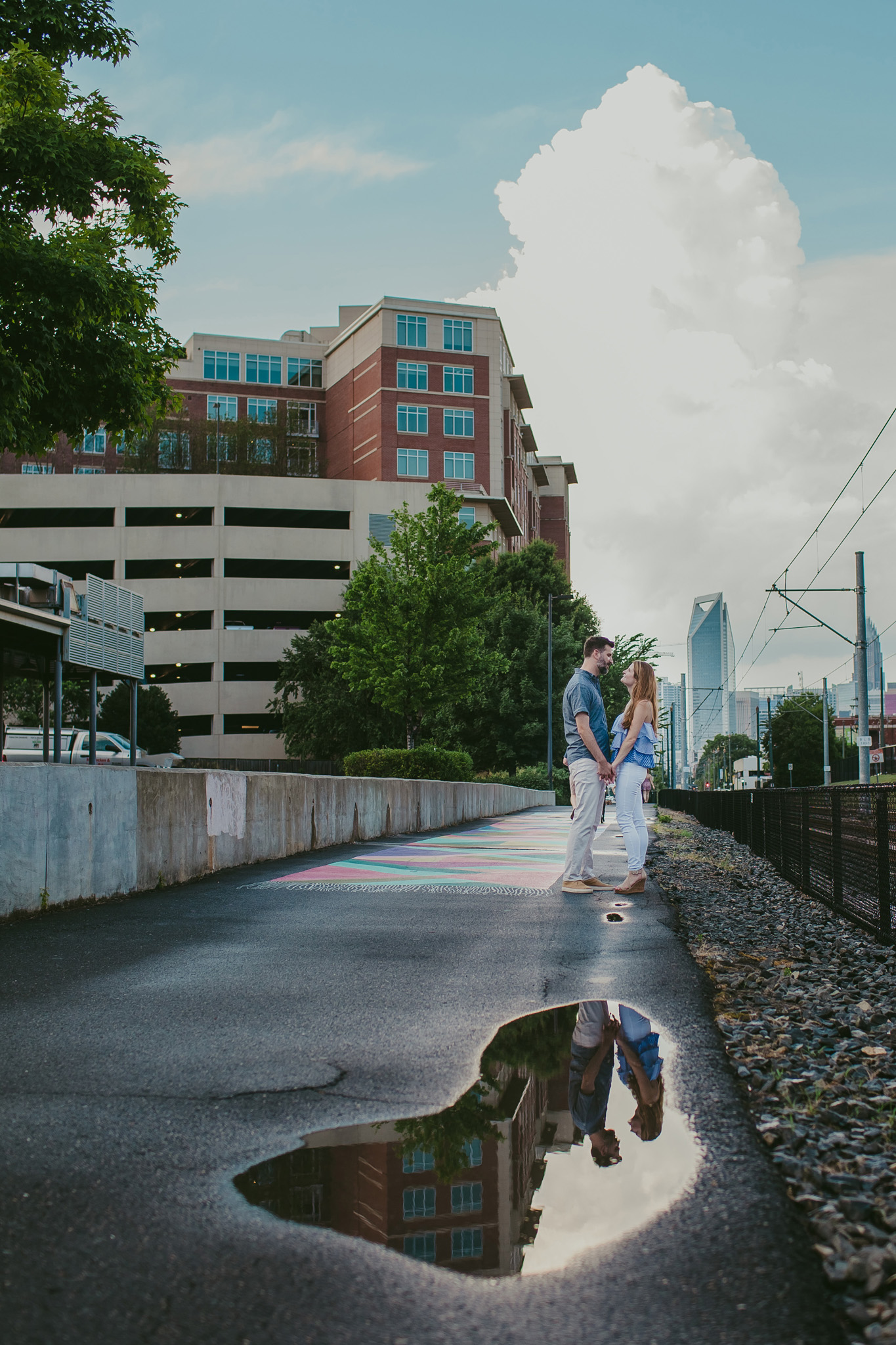 Couple snuggles at the light rail in South End Charlotte at their engagement session