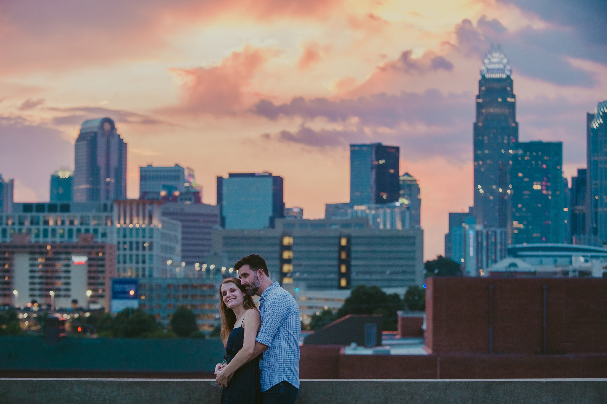 The sun sets behind the Charlotte skyline as Caroline and Stephen hug