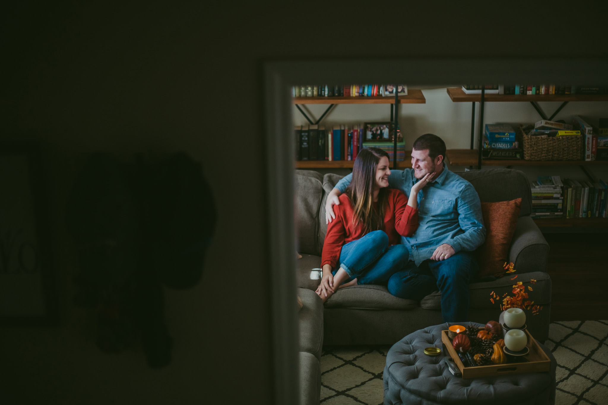 Lauren and Adam hang out on their couch during their home engagement session in Charlotte