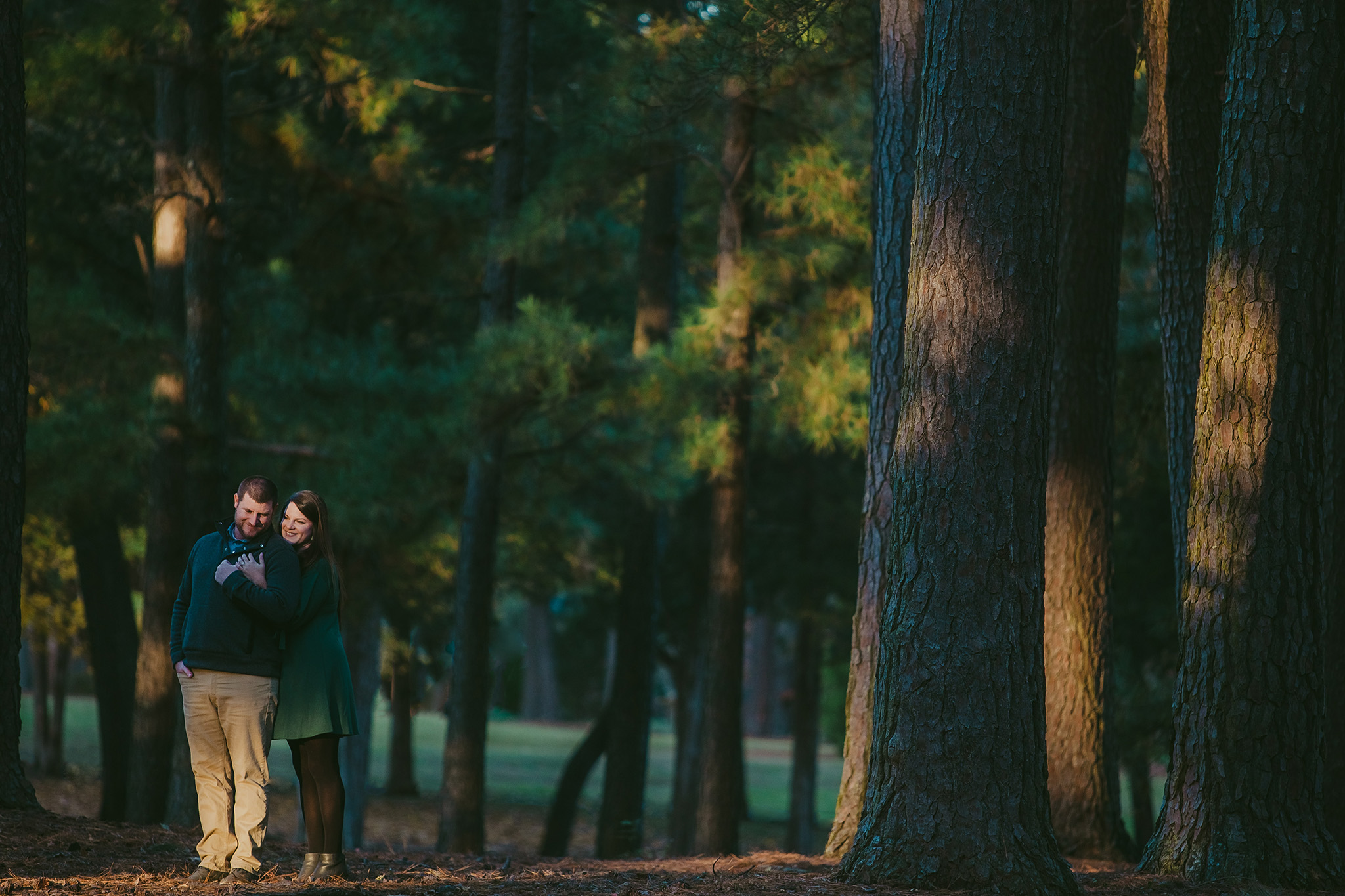 Lauren and Adam snuggle amidst the pines during their engagement session at Mac Anderson park