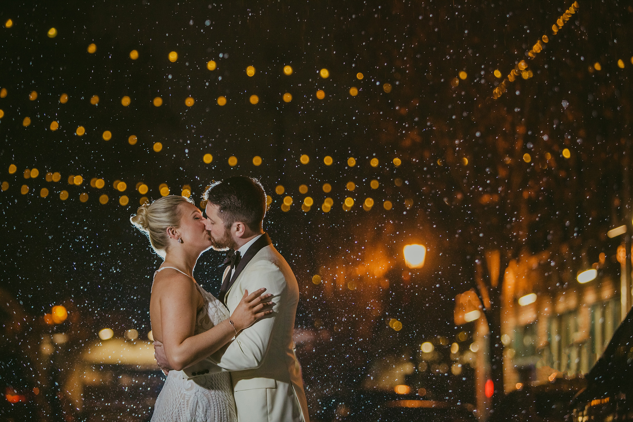 Couple kisses in the rain after their 214 Martin St. wedding in Raleigh