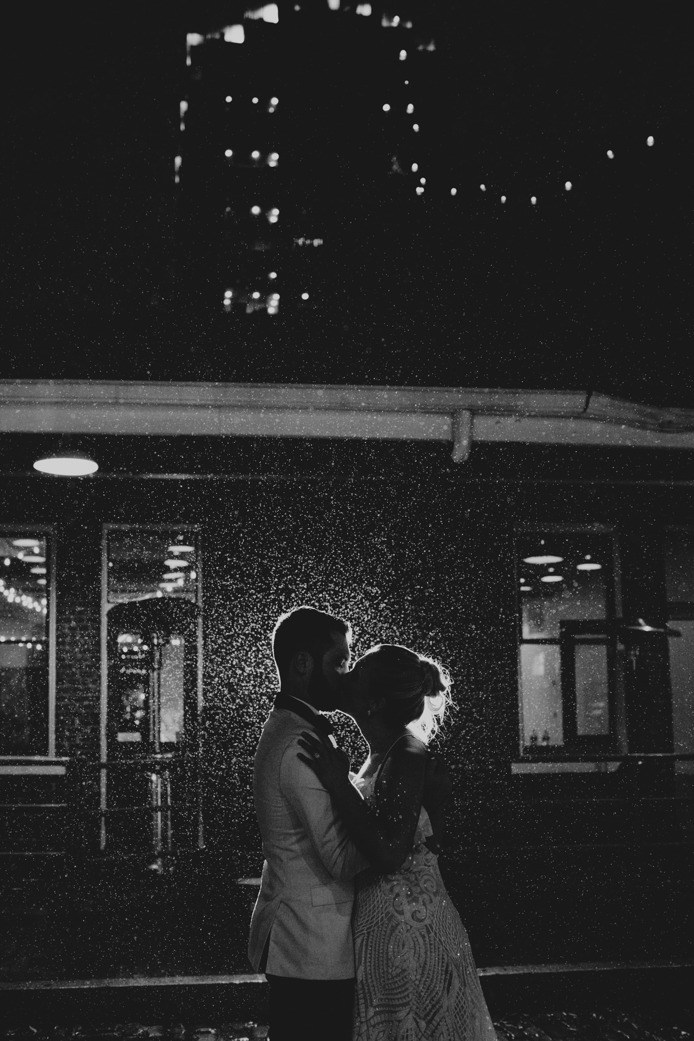 newlyweds kiss in the rain at the end of their 214 Martin St. Wedding