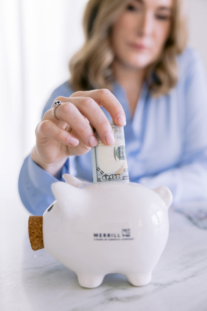 A woman adds money to a piggy bank, captured in a personal brand photoshoot for a financial advisor.