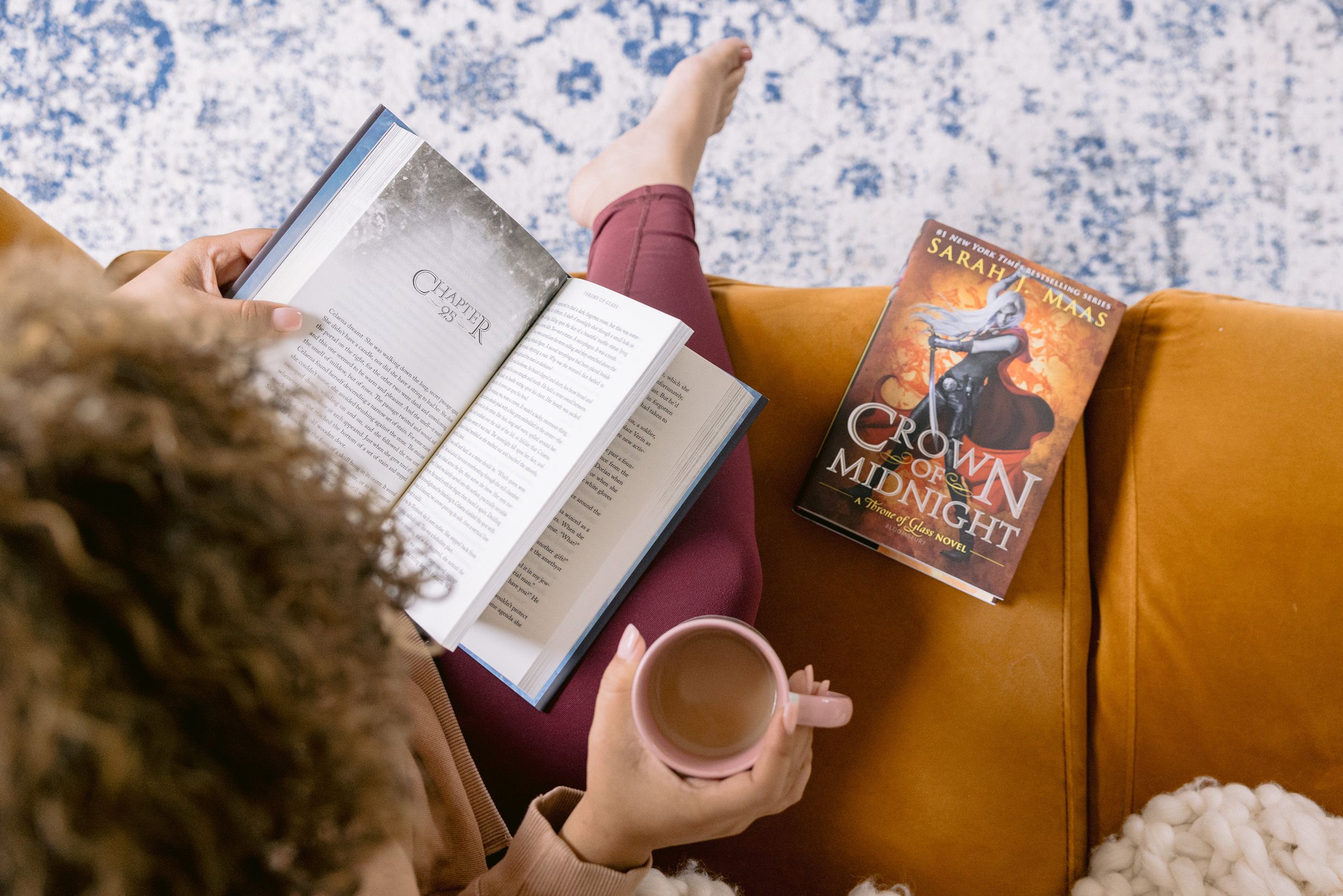 A woman reading a book on a couch, showcasing a moment of relaxation, photographed by Mabyn Ludke.