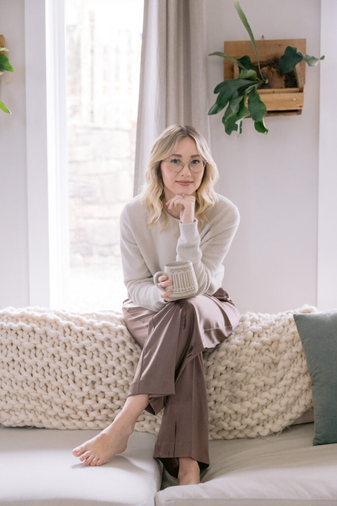  A woman on a couch with a coffee cup, embodying a casual yet polished look suitable for personal branding photography. What to wear for headshots in Charlotte NC