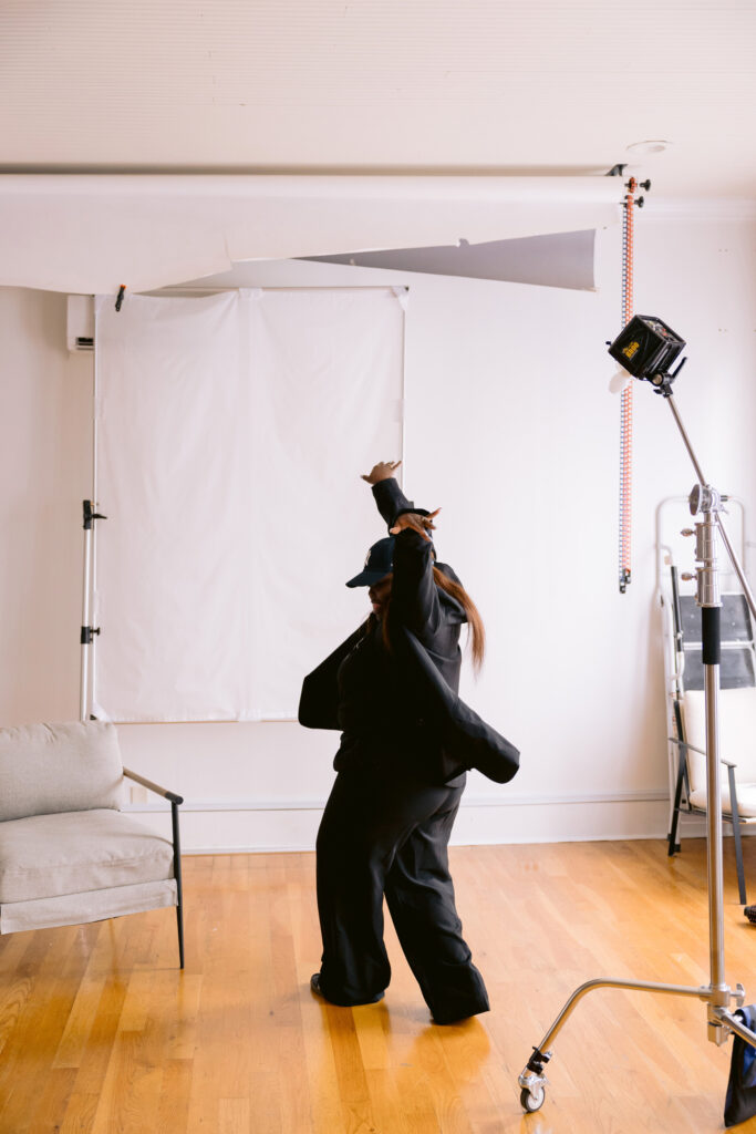 Creative woman dancing between sets in a photography studio with lighting equipment during a Lake Norman brand photography session