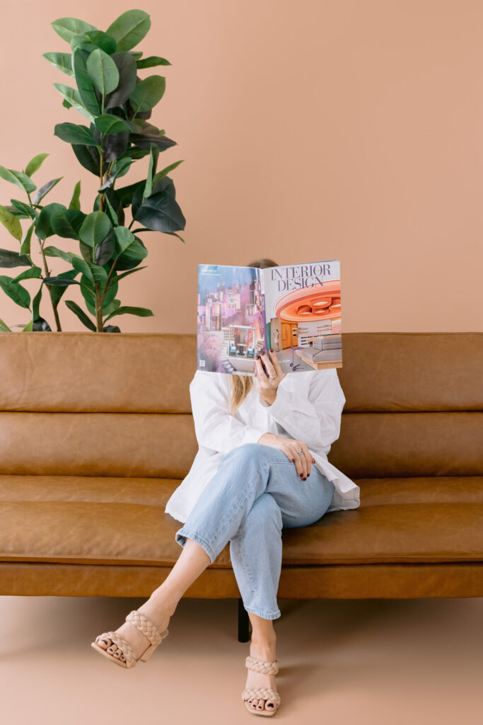 Creative professional reading an interior design magazine on a modern leather sofa during a Lake Norman brand photoshoot.